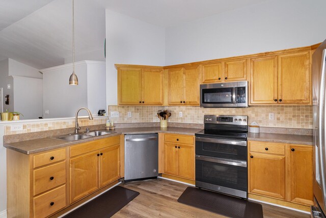 kitchen featuring sink, stainless steel appliances, backsplash, pendant lighting, and light wood-type flooring