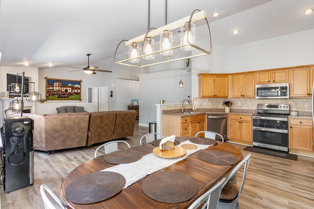 dining room with ceiling fan, light hardwood / wood-style floors, sink, and high vaulted ceiling