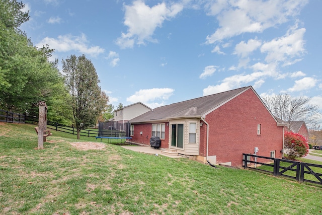 rear view of house featuring a trampoline and a yard