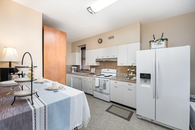 kitchen with white appliances, visible vents, a sink, under cabinet range hood, and tasteful backsplash