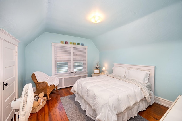 bedroom with dark wood-type flooring, radiator heating unit, baseboards, and vaulted ceiling