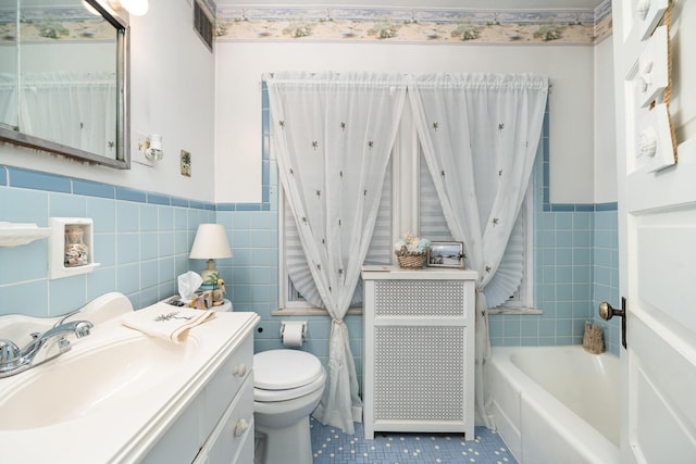 bathroom with tile patterned floors, a wainscoted wall, toilet, and tile walls