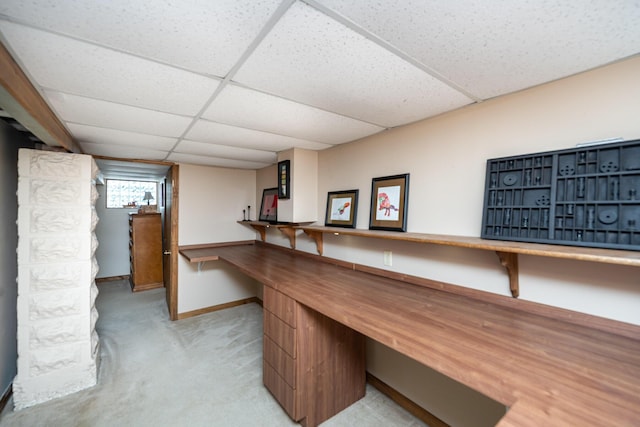 office space with a drop ceiling, light carpet, baseboards, and built in desk