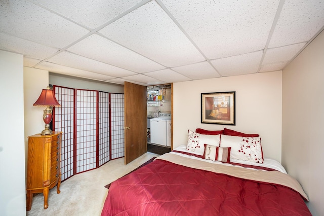 carpeted bedroom with a drop ceiling and washer / dryer