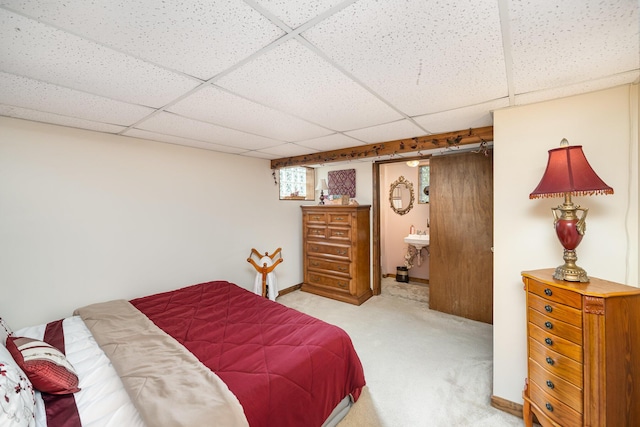 carpeted bedroom with a paneled ceiling, baseboards, and ensuite bathroom