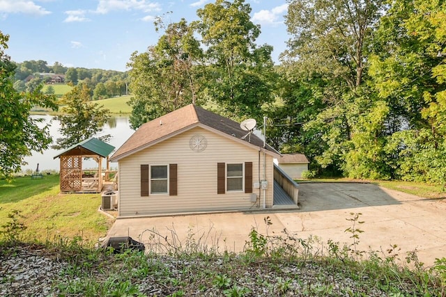 view of property exterior with a gazebo, a lawn, a water view, and central AC unit