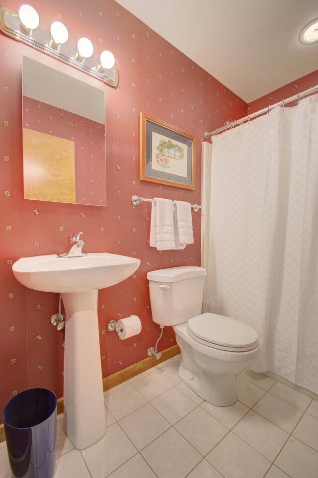 bathroom with a shower with shower curtain, tile patterned floors, and toilet