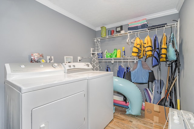 clothes washing area with washing machine and clothes dryer, crown molding, a textured ceiling, and light hardwood / wood-style floors