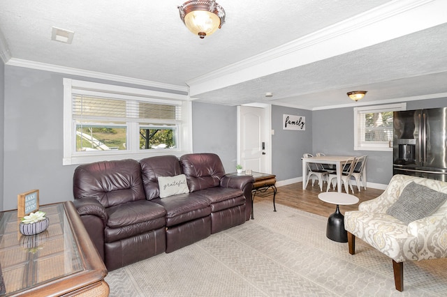 living room with a wealth of natural light, a textured ceiling, and light hardwood / wood-style floors