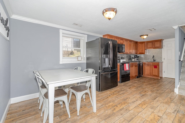 kitchen featuring black appliances, ornamental molding, light wood-type flooring, and decorative backsplash