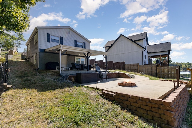 back of house with central air condition unit, a yard, ceiling fan, a patio, and a fire pit