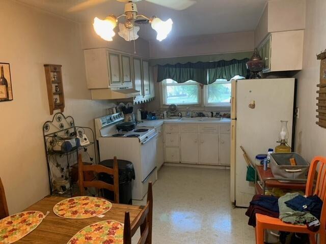 kitchen with white appliances, range hood, ceiling fan, and white cabinets