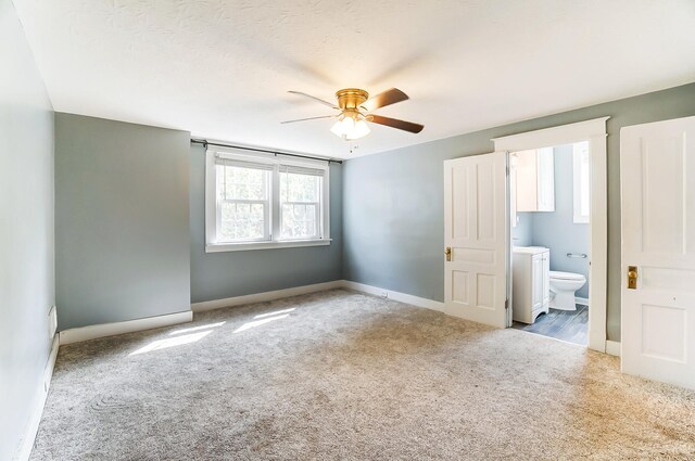 unfurnished bedroom with a textured ceiling, light colored carpet, ceiling fan, and ensuite bathroom