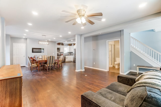 living room with ceiling fan and dark hardwood / wood-style flooring