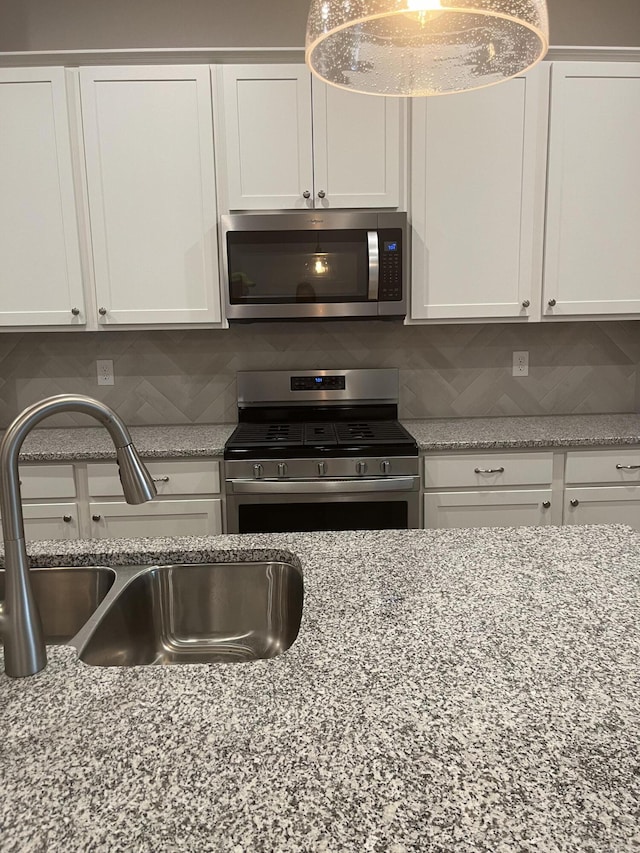 kitchen featuring stainless steel appliances, sink, backsplash, and white cabinets