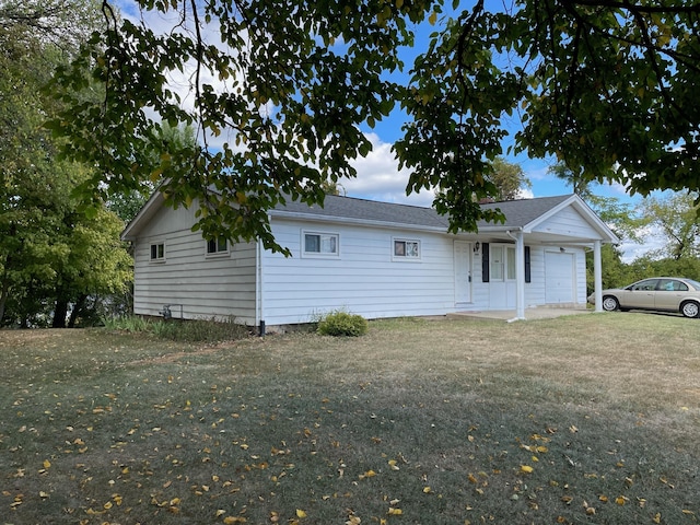 rear view of property with a garage and a lawn