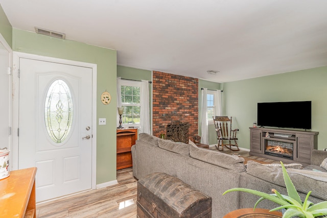 interior space featuring light wood-type flooring and a brick fireplace