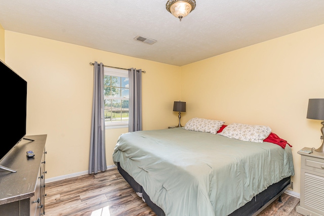 bedroom with light wood-type flooring and a textured ceiling