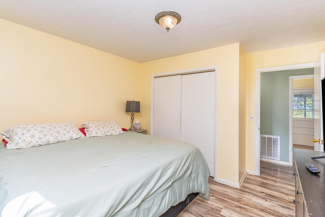 bedroom featuring light wood-type flooring, a textured ceiling, and a closet