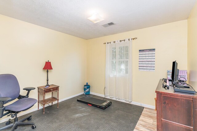 office area with a textured ceiling and light hardwood / wood-style flooring