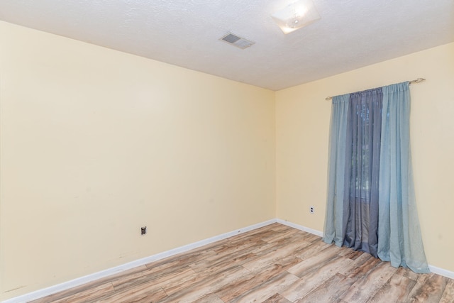 empty room featuring a textured ceiling and light hardwood / wood-style flooring