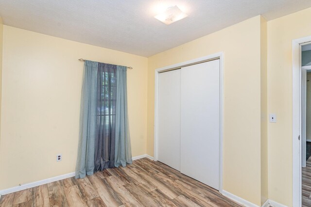 unfurnished bedroom with a textured ceiling, a closet, and wood-type flooring