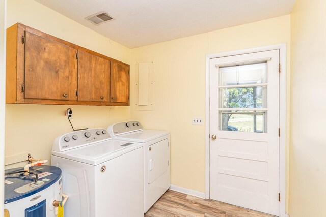 clothes washing area with water heater, independent washer and dryer, cabinets, and light hardwood / wood-style flooring