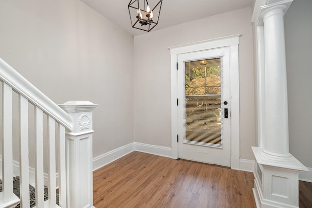 doorway featuring ornate columns, a notable chandelier, and light hardwood / wood-style floors