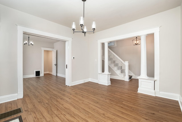 empty room featuring ornate columns, a notable chandelier, and dark hardwood / wood-style floors