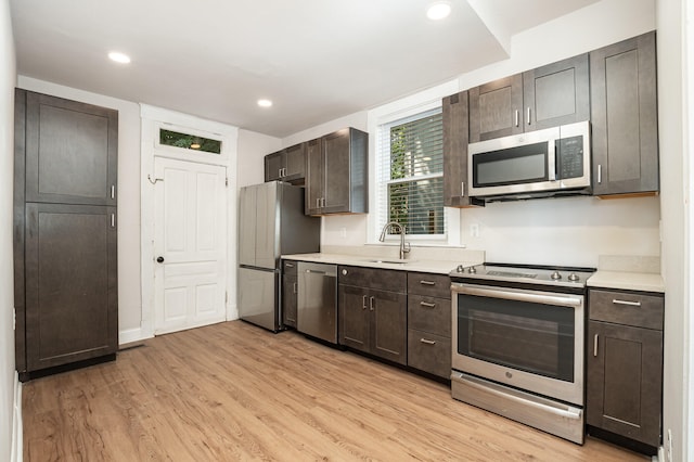 kitchen featuring sink, stainless steel appliances, dark brown cabinetry, and light hardwood / wood-style floors