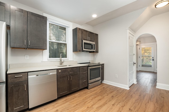 kitchen featuring stainless steel appliances, sink, dark brown cabinetry, and light wood-type flooring