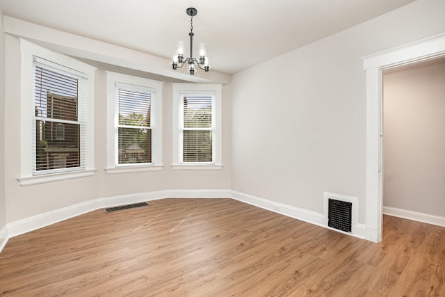 spare room with light hardwood / wood-style flooring and an inviting chandelier