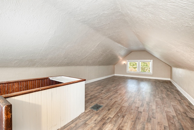 bonus room with a textured ceiling, vaulted ceiling, and wood-type flooring