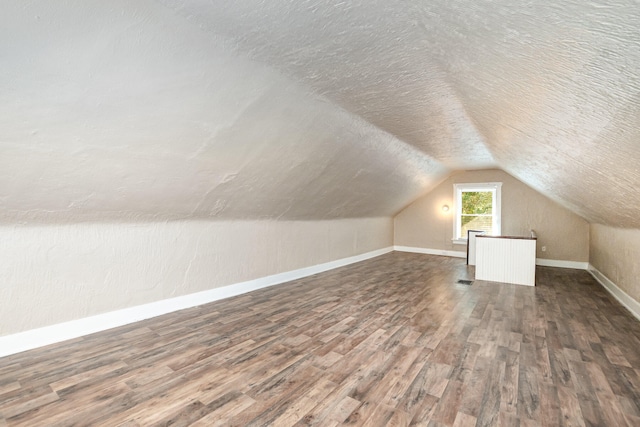 bonus room featuring lofted ceiling, dark hardwood / wood-style flooring, and a textured ceiling