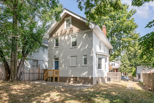 rear view of property featuring a yard and central AC unit