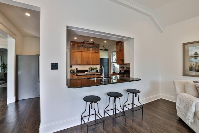 kitchen with dark hardwood / wood-style flooring, pendant lighting, a kitchen bar, kitchen peninsula, and sink