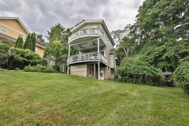 rear view of house featuring a balcony, a yard, and ceiling fan