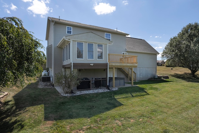 rear view of property featuring a lawn, a hot tub, and a deck