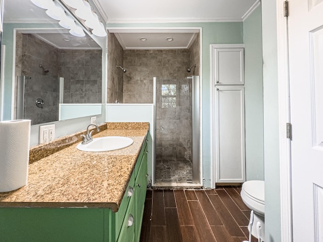 bathroom featuring a shower with door, vanity, toilet, ornamental molding, and hardwood / wood-style flooring