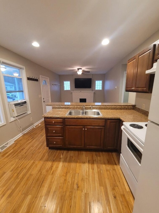 kitchen featuring cooling unit, kitchen peninsula, sink, and white range with electric stovetop