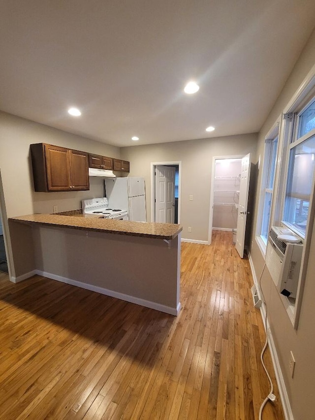 kitchen with light hardwood / wood-style floors, cooling unit, white appliances, and kitchen peninsula