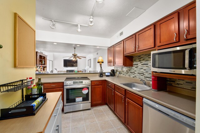 kitchen with kitchen peninsula, appliances with stainless steel finishes, tasteful backsplash, a textured ceiling, and ceiling fan