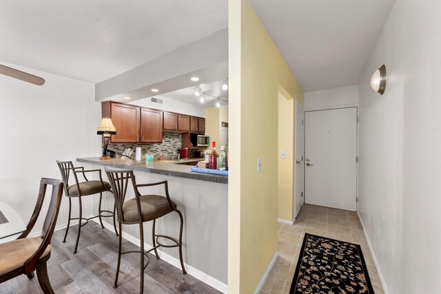 kitchen with kitchen peninsula, decorative backsplash, and a kitchen bar