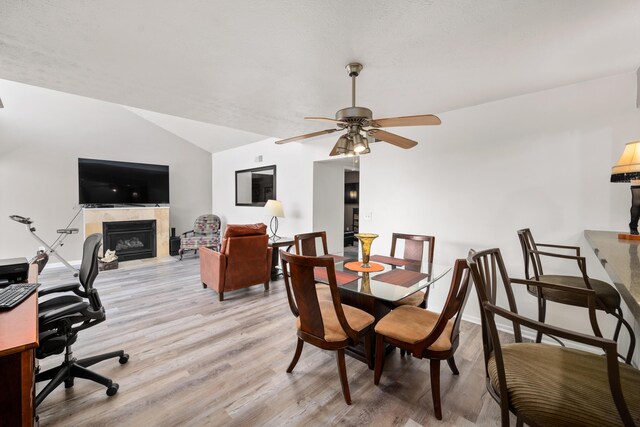 dining room with ceiling fan, vaulted ceiling, and light hardwood / wood-style flooring