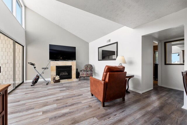 living room with a tile fireplace, light hardwood / wood-style flooring, and high vaulted ceiling