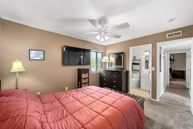 bedroom featuring hardwood / wood-style floors, ensuite bath, and ceiling fan