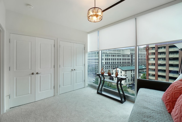 living area with a chandelier, light colored carpet, and expansive windows