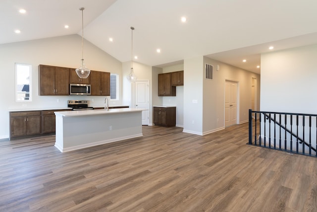 kitchen with stainless steel appliances, dark hardwood / wood-style flooring, sink, and a center island with sink