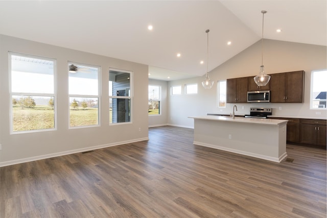 kitchen featuring appliances with stainless steel finishes, pendant lighting, an island with sink, dark wood-type flooring, and dark brown cabinets