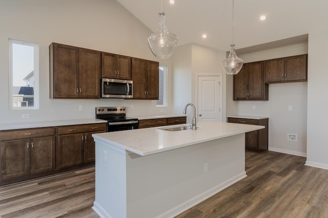 kitchen with sink, dark brown cabinets, pendant lighting, stainless steel appliances, and a kitchen island with sink